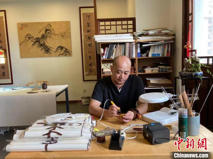陶思俊正在進行葫蘆烙畫創(chuàng)作?！￡愳o 攝