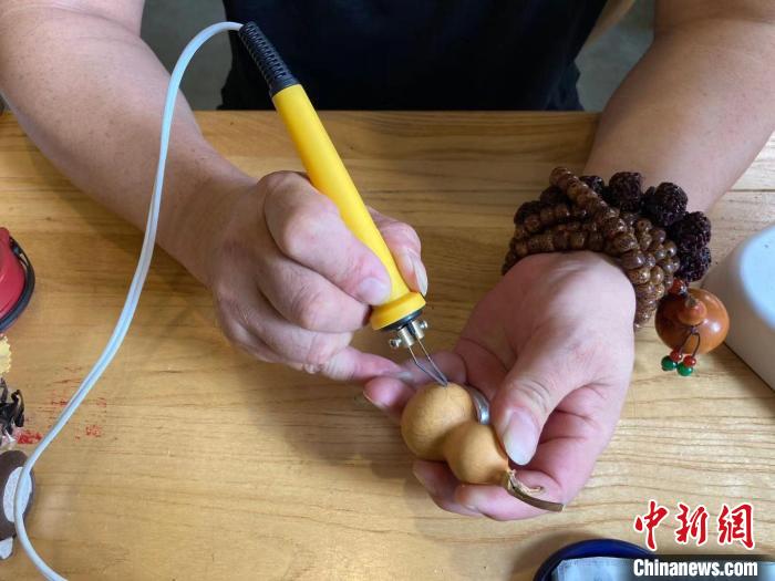 陶思俊正在進行葫蘆烙畫創(chuàng)作?！￡愳o 攝