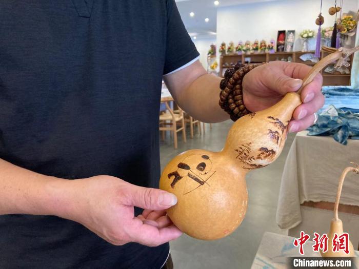 陶思俊展示自己創(chuàng)作的葫蘆烙畫?！￡愳o 攝