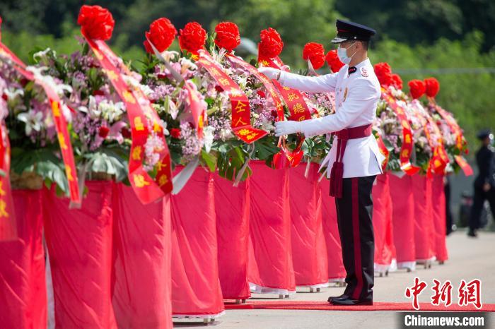 香港特區(qū)政府消防處處長梁偉雄在儀式上整理花籃上的挽帶?！≌侣勌幑﹫D