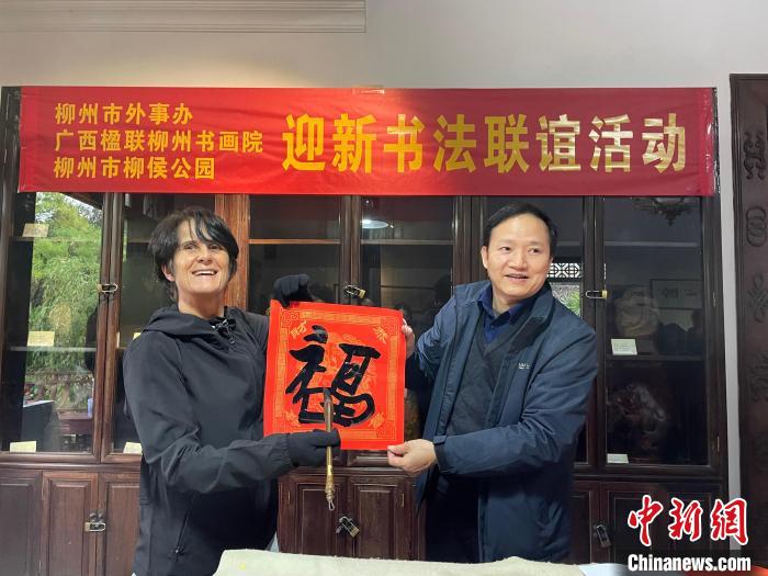 圖為一名英國人(左)展示其書寫的春聯(lián)?！×周?攝