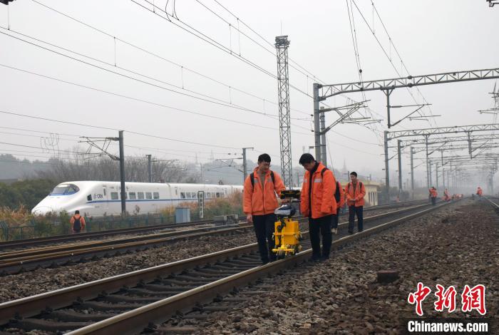 圖為探傷工使用鋼軌探傷儀對京九線廬山站區(qū)鋼軌進(jìn)行檢測，臨近的昌九城際線上一列動車組呼嘯而過?！⊥鹾?攝