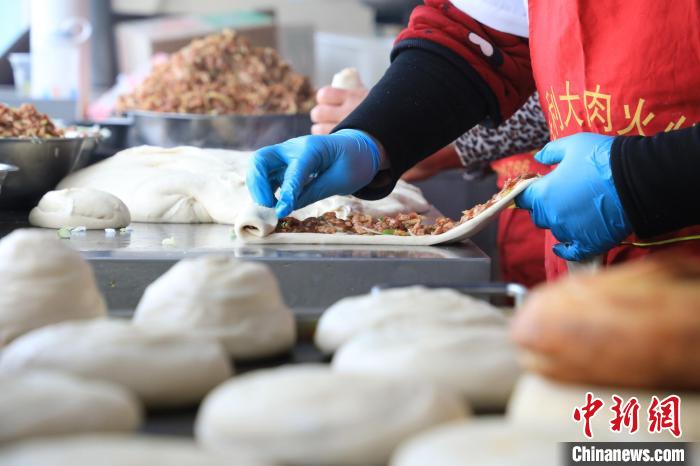 “火燒”師傅們將面劑拉長(zhǎng)，抹上肉餡，再卷成陀螺狀，旋磨成型后壓平?！∴囆?qiáng) 攝