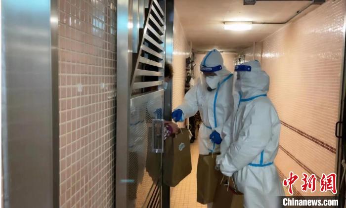 圖為吳學(xué)明和義工送抗疫物資到確診家庭手中?！∈茉L者供圖