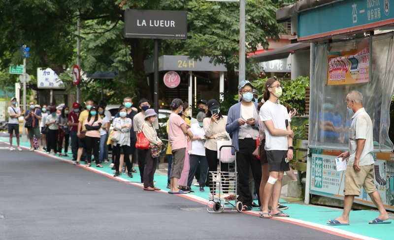 圖為民眾在藥局前大排長(zhǎng)龍等待購(gòu)買快篩試劑。（陳俊吉攝）