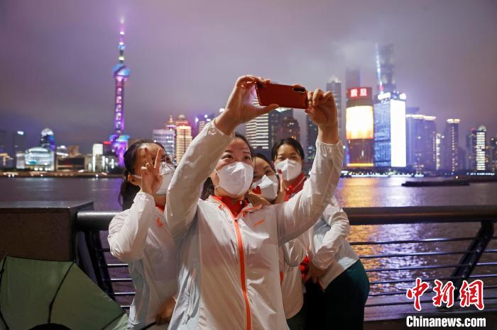 華中科技大學同濟醫(yī)學院附屬同濟醫(yī)院援滬醫(yī)療隊隊員冒雨在外灘濱江步道上合影?！∫罅⑶?攝