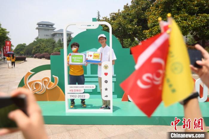 大學(xué)生在校園內(nèi)拍攝校慶主題照片。　泱波 攝