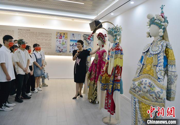 圖為福建省實(shí)驗(yàn)閩劇院工作人員為研學(xué)體驗(yàn)營學(xué)生介紹閩劇戲服。　張斌 攝