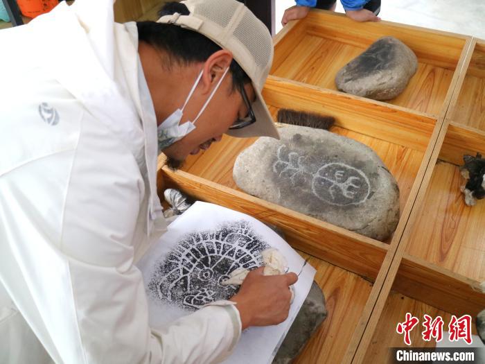 臺青用墨包為巖畫印記上色?！±钤?攝