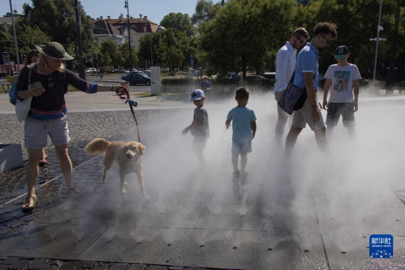 7月19日，在匈牙利布達佩斯，人們在一處公共加濕設施享受清涼的噴霧。（圖源：新華社）