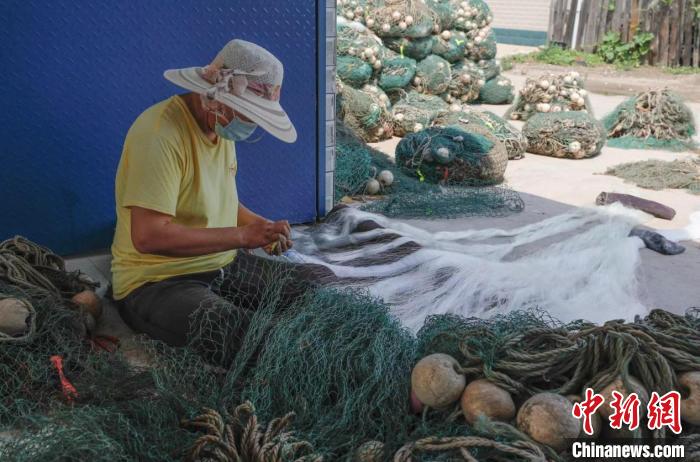 河北省唐山市豐南區(qū)黑沿子鎮(zhèn)漁民高貴娟正在補(bǔ)網(wǎng)。　陳軍 攝