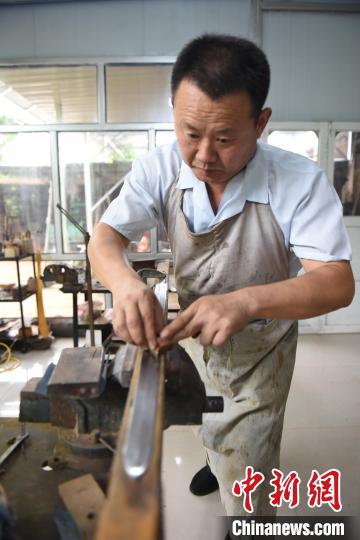 王二兵對燒制好的劍進(jìn)行修磨?！「哒挤?攝