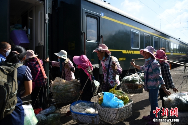 圖為8月9日，菜農(nóng)挑著籃子準(zhǔn)備登車。 <a target='_blank' href='/'>中新社</a>記者 劉冉陽 攝