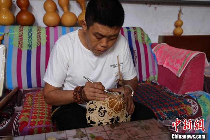 馮計剛在雕刻葫蘆作品。　孔飛 攝