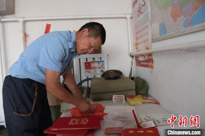 圖為謝建民整理當(dāng)兵時(shí)的榮譽(yù)證書?！『鷸|育 攝