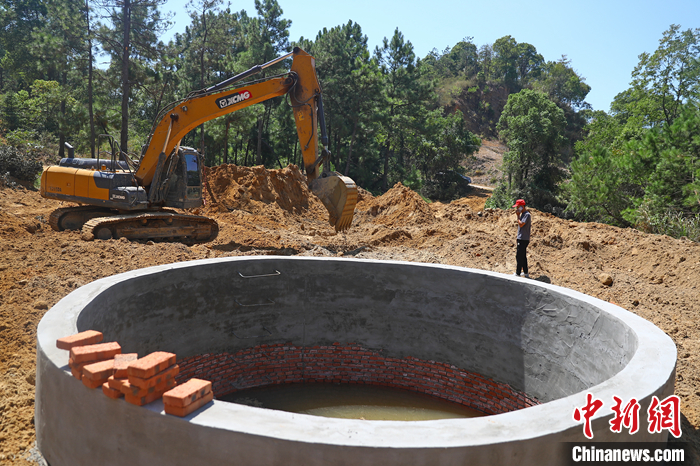9月6日，在鄱陽湖畔的江西省九江市都昌縣多寶鄉(xiāng)林場，一臺挖掘機不停揮舞著“大臂”，為一口直徑5米、深8.5米的蓄水池進行場地平整，山泉水順著一根水管緩緩注入蓄水池內(nèi)。 <a target='_blank' href='/'>中新社</a>記者 劉占昆 攝