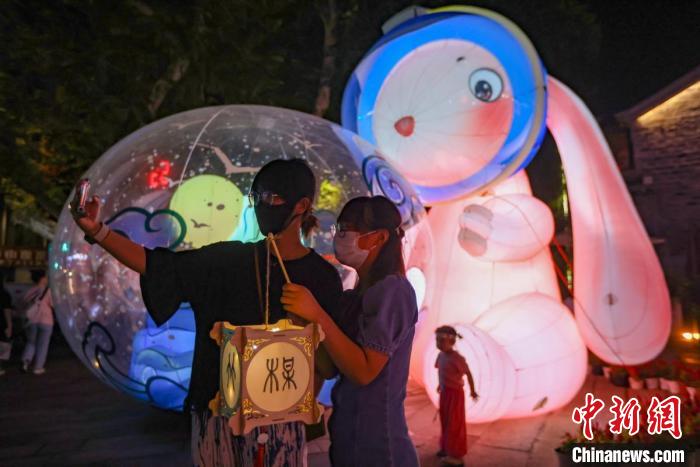 年輕人在燈市擺放著的“兔子燈”前留影?！°蟛?攝