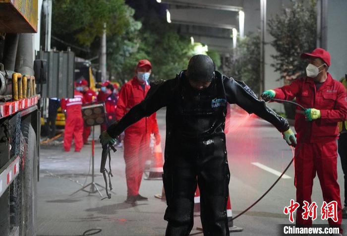 圖為“市政蛙人”出井后沖洗身上的工作服?！【琶赖┰?攝