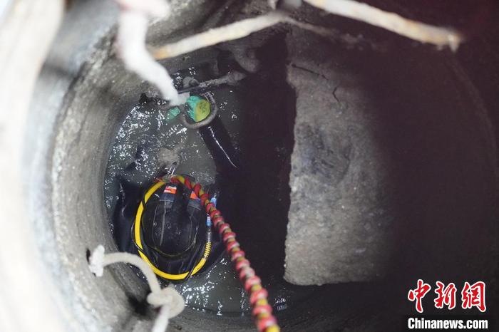 圖為“市政蛙人”穿著厚重的潛水服在狹小的污水井里作業(yè)。　九美旦增 攝