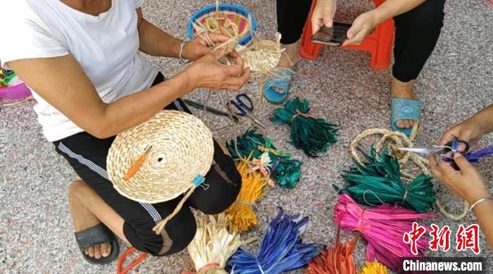 眾人正在用彩色玉米皮編織工藝品?！⒖÷?　攝