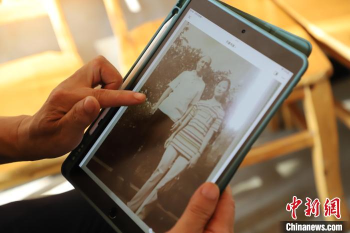 圖為廖奕斌查看老照片?！≈貞c榮昌區(qū)委臺(tái)辦供圖