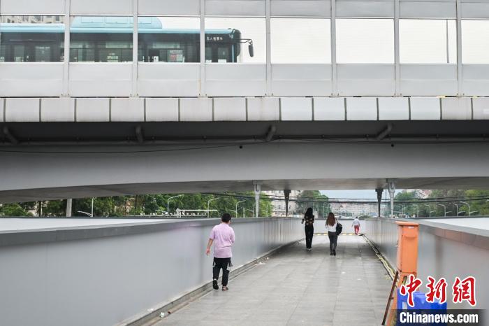 圖為市民走在天橋上，公交車從頭頂?shù)缆否傔^?！∨硇拟?攝