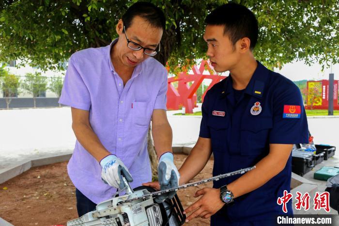 廠家人員(左)向庫管員介紹油鋸的拆卸規(guī)范?！⒚详?攝