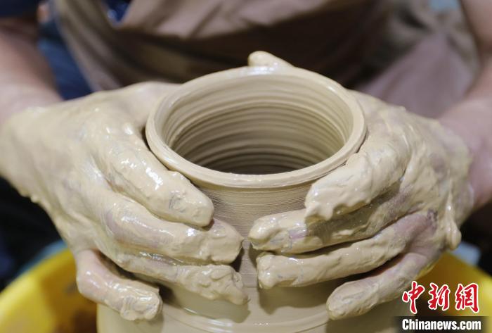 圖為張明正在進行創(chuàng)意陶藝的定形工序。　門叢碩 攝