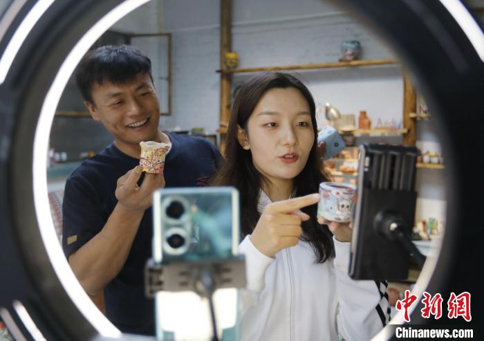 圖為張明與同事通過網(wǎng)絡直播形式介紹創(chuàng)意陶藝產(chǎn)品?！￠T叢碩 攝