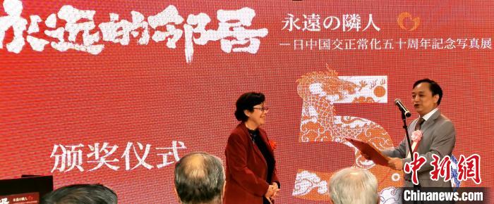 攝影展實行委員會中方代表劉莉生代表多元文化會館向日本前駐華大使阿南惟茂夫人阿南史代頒發(fā)獎狀?！≈鬓k方供圖