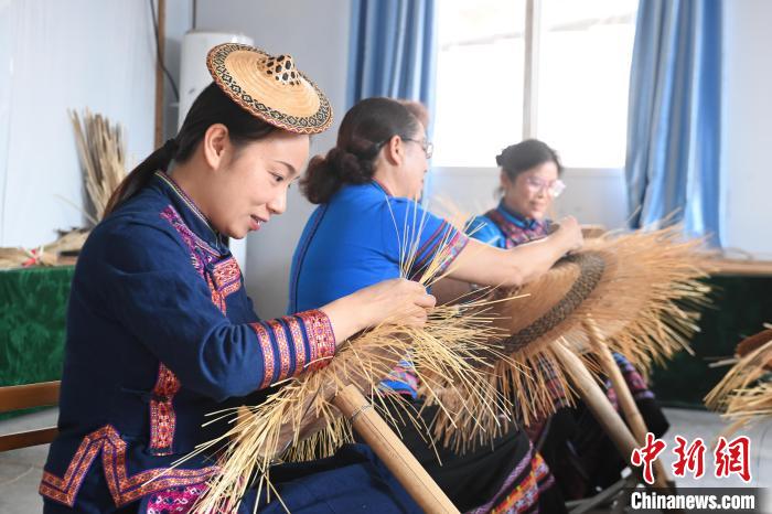 覃敏(左)和母親(中)在編織花竹帽?！⊥跻哉?攝