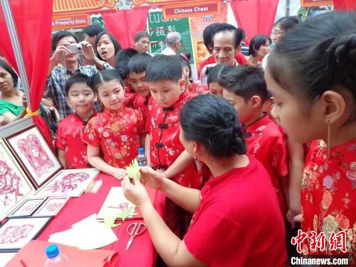 資料圖。2013年，正值中國(guó)新年，吳立喜在菲律賓馬尼拉市為菲律賓的華裔學(xué)生現(xiàn)場(chǎng)教學(xué)剪紙?！橇⑾补﹫D