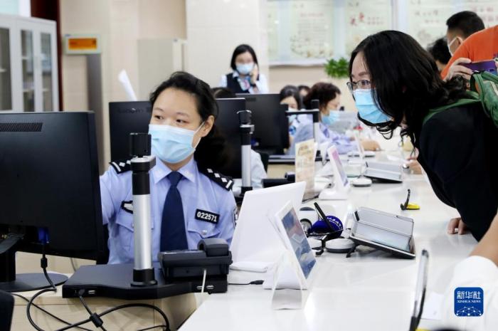 2020年10月14日，原籍浙江湖州的王秀麗(右)在上海市徐匯漕河涇社區(qū)事務受理服務中心公安綜合窗口辦理戶口遷移手續(xù)，成為享受上海市公安局會同浙江省公安廳共同推出的滬浙“跨省市戶口網上遷移”便民措施的第一人。新華社記者 方喆 攝