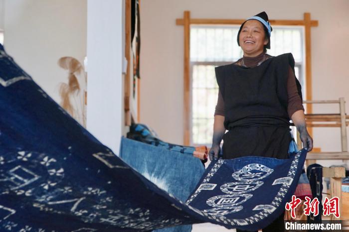 圖為黎鳳珍正在展示使用藍(lán)靛染工藝制作的條幅?！№f國(guó)政 攝