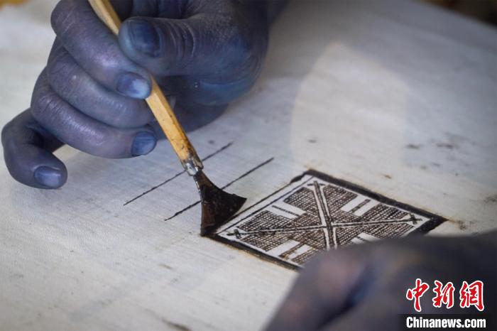 圖為黎鳳珍正手持著粘膏刀繪制“瑤王印”?！№f國(guó)政 攝