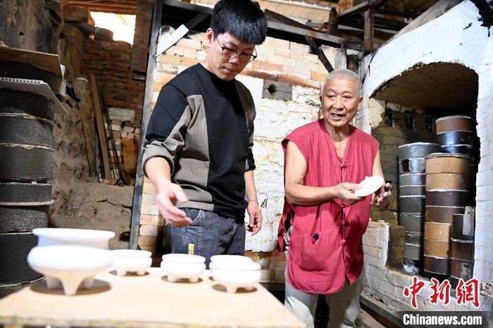 在窯口，林俊徒弟把已上釉的素坯傳給師傅?！埥鸫?攝