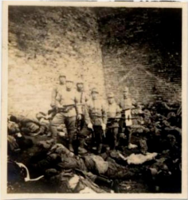 黑黑的城墻下面，是被日軍屠殺的累累尸首。日軍士兵手持步槍刺刀和日本軍旗，站在中國(guó)人的尸體旁炫耀著所謂的“武威”。圖源：侵華日軍南京大屠殺遇難同胞紀(jì)念館網(wǎng)站