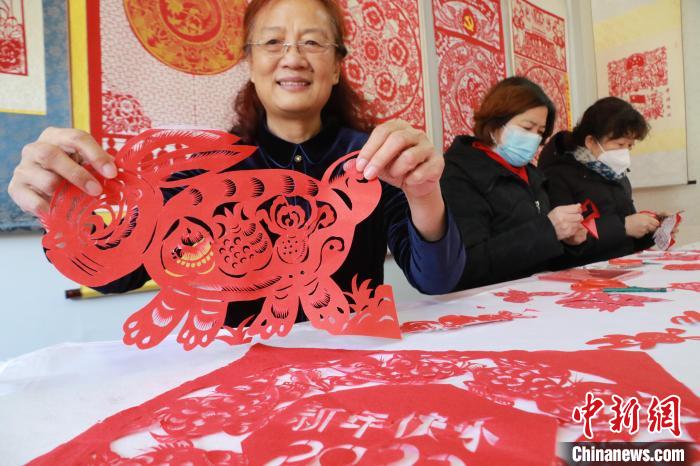 非遺傳承人董雙強(qiáng)在展示自己創(chuàng)作的剪紙作品?！±詈?攝