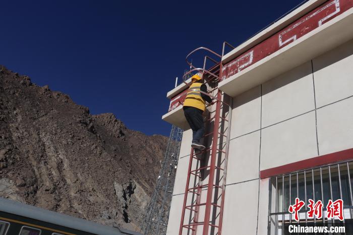 圖為馬智文利用古榮站站房爬梯進行攀爬作業(yè)。　 馬生明 攝