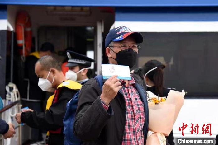 搭乘泉金航線的乘客展示手中的船票?！∪?攝