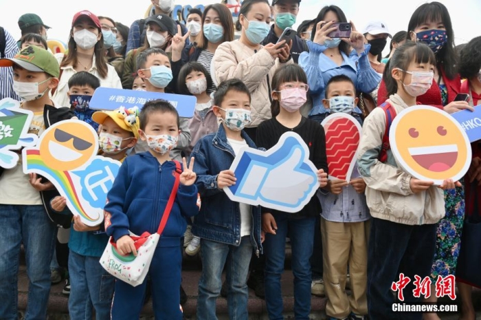 隨著香港與內(nèi)地全面“通關(guān)”，香港不少旅游活動重啟。2月11日上午，香港海洋公園迎來全面復(fù)常后的首個內(nèi)地點(diǎn)對點(diǎn)旅行團(tuán)。該旅行團(tuán)約有140名內(nèi)地旅客由深圳蓮塘口岸乘坐跨境專車直達(dá)香港海洋公園，園方特地為旅行團(tuán)安排歡迎儀式，歡迎他們蒞臨香港海洋公園。圖為兒童手持表情圖案合影。李志華 攝