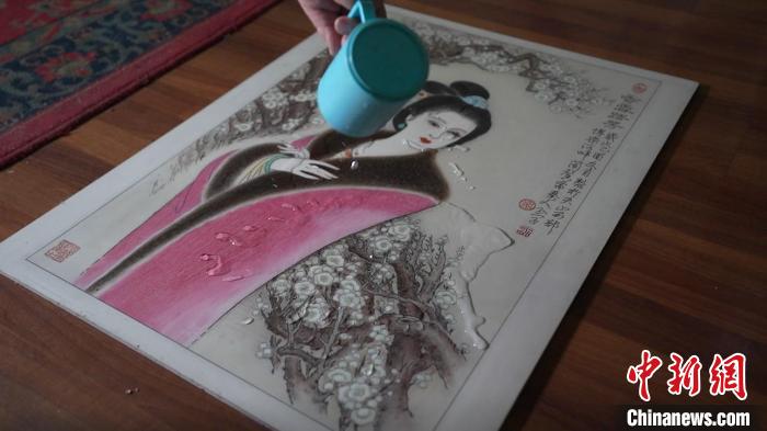 藺烈演示在板刻線畫作品上做防水試驗(yàn)，展示作品不僅防水還不掉色，濕水后還可用布擦拭。　戎睿 攝