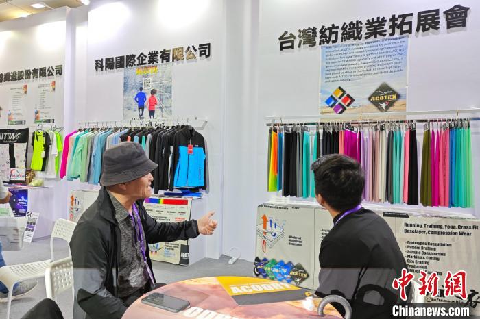臺商邱鶴銘(左)在展位上介紹新研發(fā)的功能面料?！枪跇?biāo) 攝