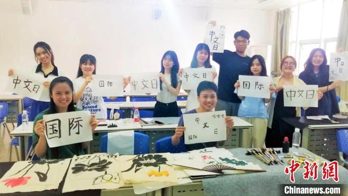 圖為留學(xué)生在展示書法作品?！±捉鹧?攝