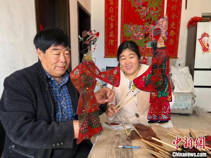 圖為馮克獻(xiàn)和女兒展示制作完成的皮影道具?！●R瑾 攝