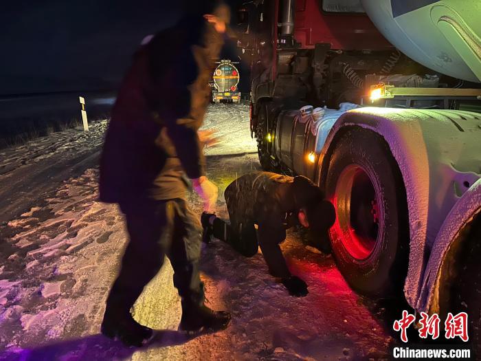 圖為民警幫助受困車輛安裝防滑鏈。　果洛州委宣傳部供圖