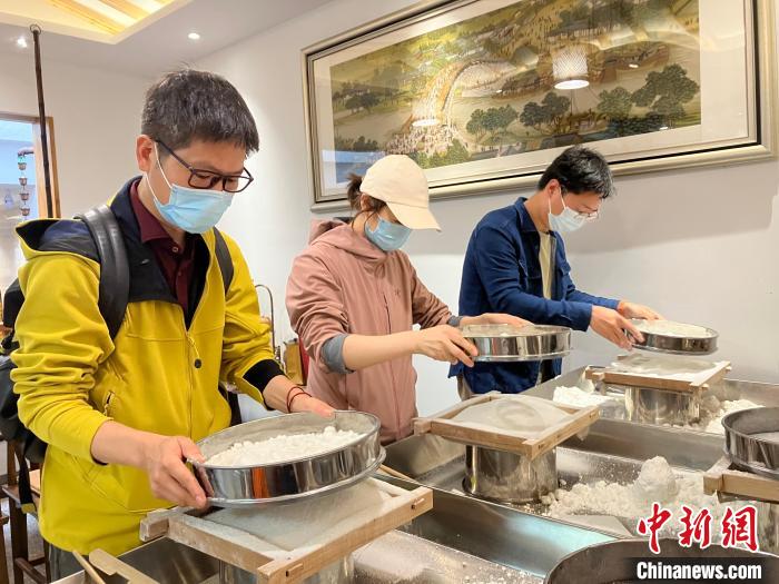 記者篩粉，嘗試制作梁弄大糕 胡豐盛 攝