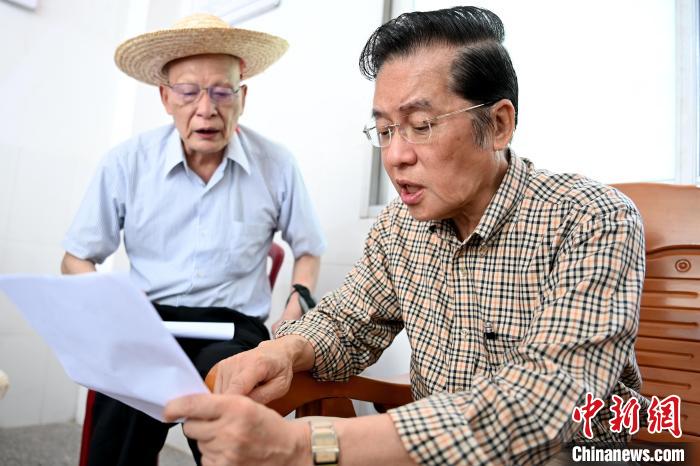 張榮恭(右)在詔安縣秀篆鎮(zhèn)北坑村與族親比對族譜。　張金川 攝