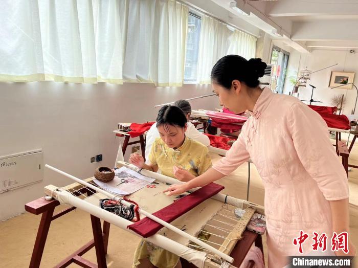 圖為陶衛(wèi)華正在指導(dǎo)繡坊的繡娘刺繡?！±铐嵑?攝