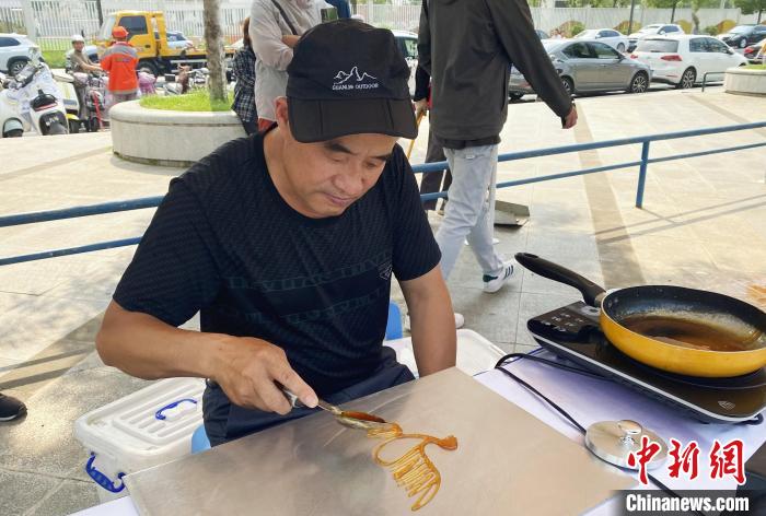 民間藝人現(xiàn)場(chǎng)演示糖畫(huà)。　崔佳明 攝